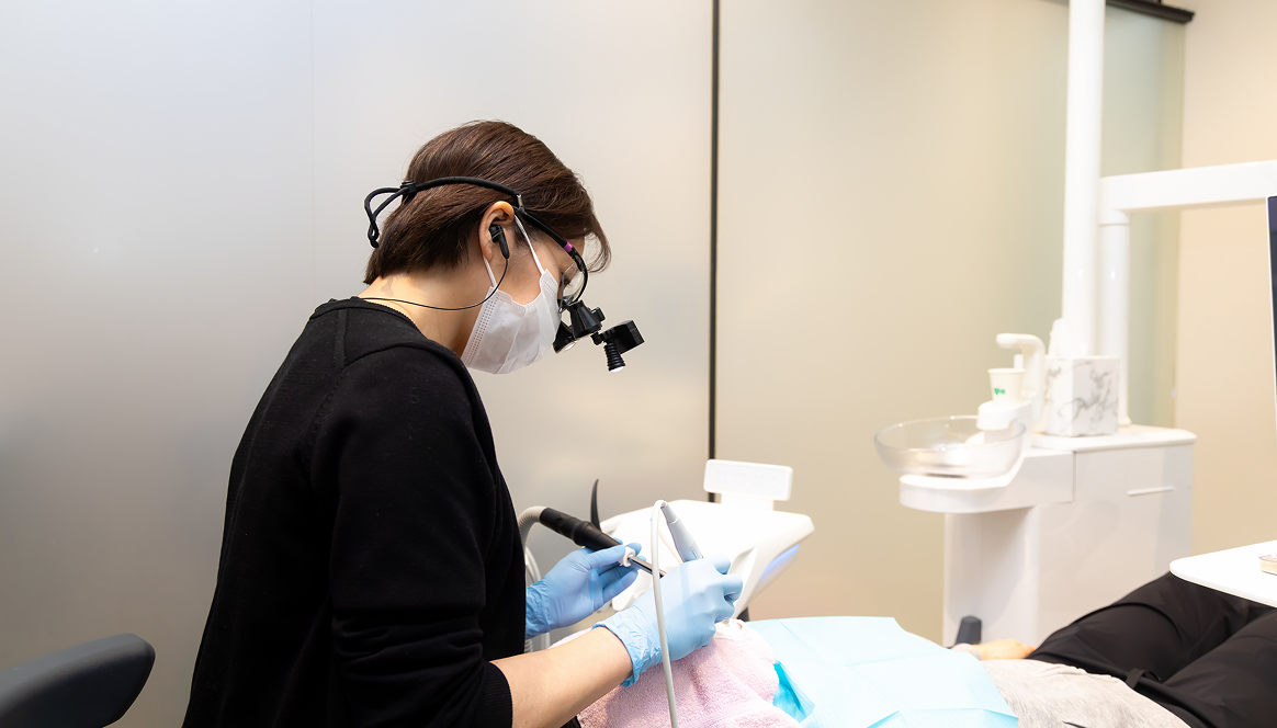認定歯科衛生士が拡大鏡を用いてメインテナンスを行う様子
